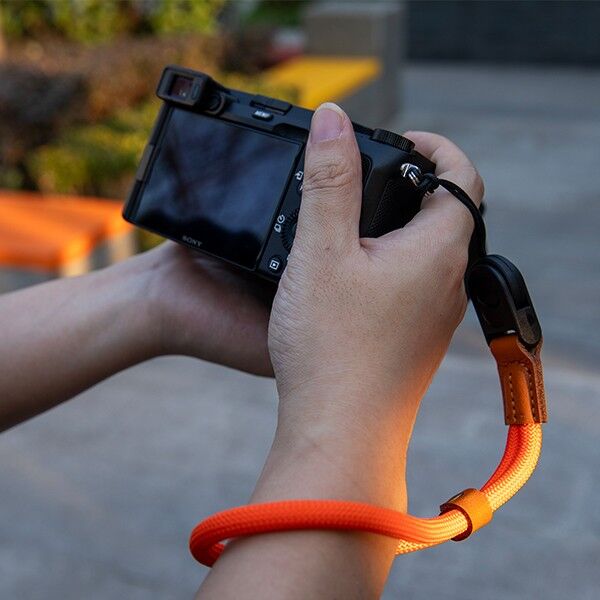 Haida orange wrist strap attached to a camera in use