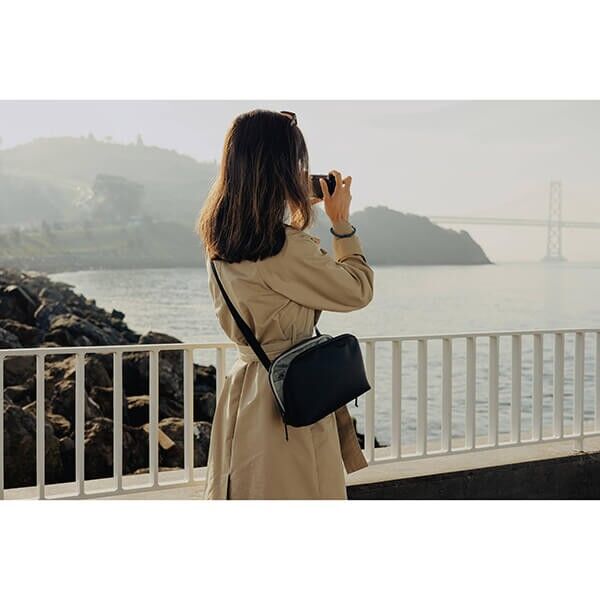 Peak Design Travel Crossbody Bag in Black, Sling Bag for Camera and Everyday Use in Front of a Bridge Peak Design Travel Crossbody Bag in Black, Sling Bag for Camera and Everyday Use in Front of a Bridge